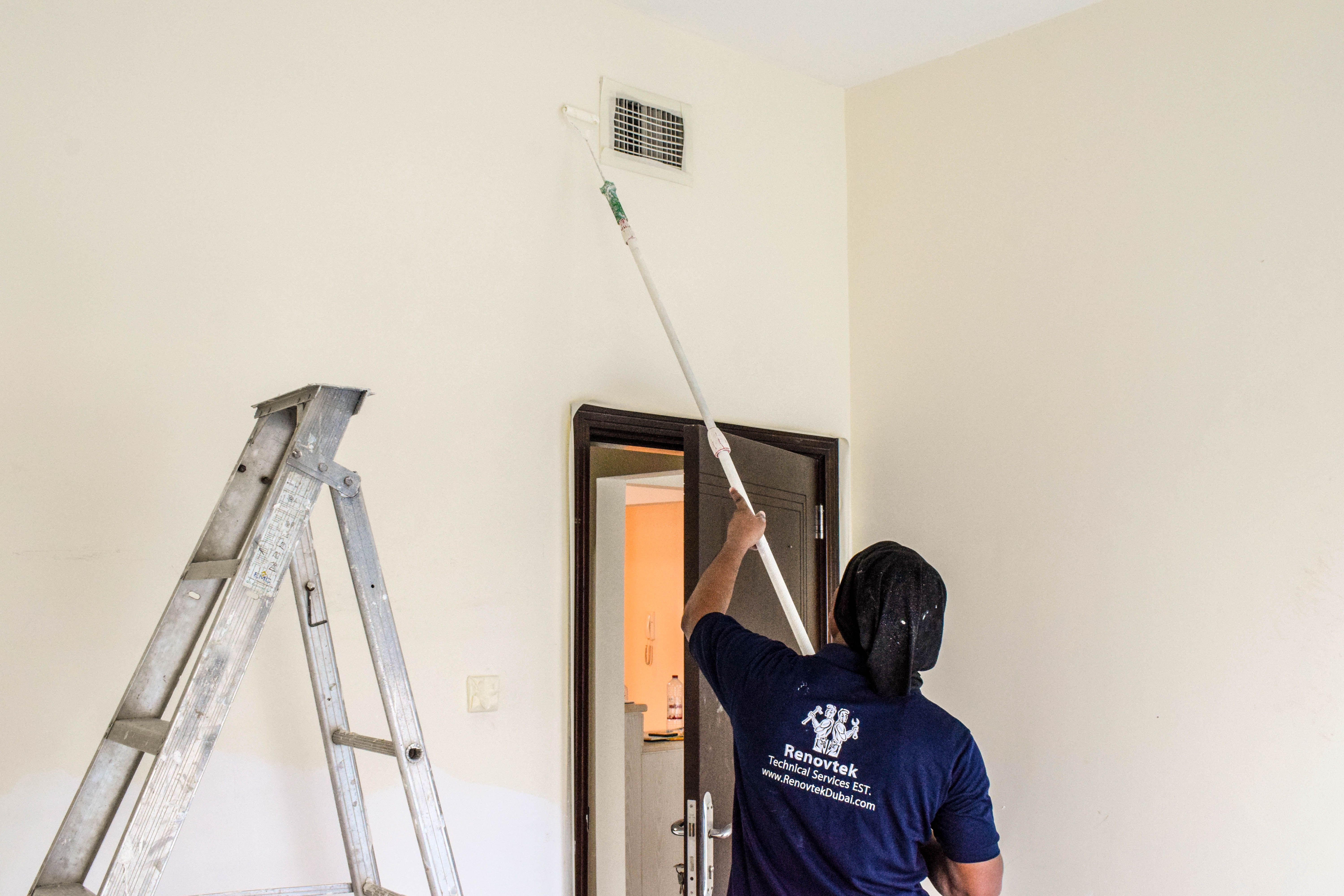 A painter is painting a wall using a roller